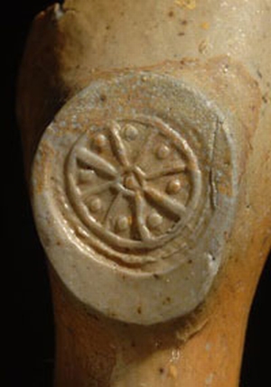 Wheel symbol with pellets between the spokes, stamped in relief on the base of the heel of a pipe dated to c 1610-40.
